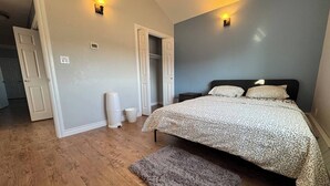 Un dormitorio con una cama, una alfombra gris y dos luces fijadas a la pared.