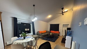 Un espacio habitable compacto con zona de comedor, un sofá, una mesa de centro y un dispensador de agua.