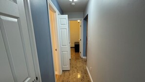Un pasillo con suelo de madera, puertas blancas y paredes azules.
