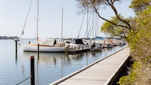 A wooden dock extending into calm water with several boats moored at the dock. - Parachilna at Boardwalk Villas Metung (Metung)
