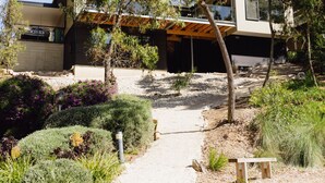 A modern house with a covered outdoor area, surrounded by various plants and a gravel path. - Parachilna at Boardwalk Villas Metung (Metung)