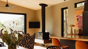 A modern kitchen with a large window, a black stove, and a dining area with a wooden table and chairs. - Parachilna at Boardwalk Villas Metung (Metung)