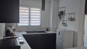 A modern kitchen with a central island, black cabinets, white countertops, a built-in oven, and a hanging pendant light. - Gîte Un instant de rêve in Dorlisheim, heated indoor pool, sauna (Dorlisheim)