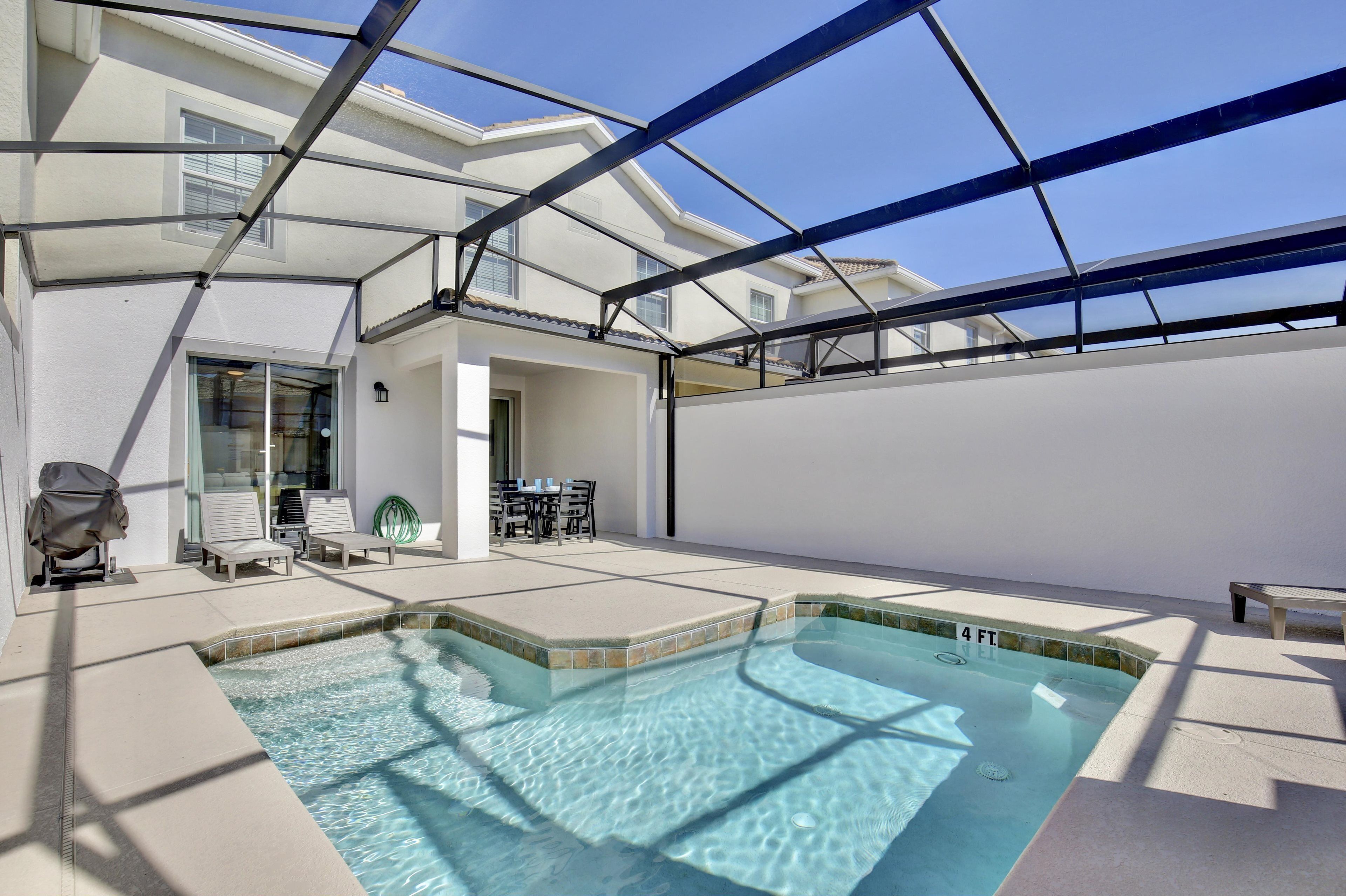 A rooftop pool area with a glass enclosure, lounge chairs, and a table.