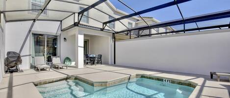 A rooftop pool area with a glass enclosure, lounge chairs, and a table.