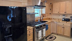 Une cuisine moderne avec des panneaux en bois, des appareils en acier inoxydable et un îlot central.