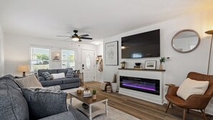 A modern living room with a fireplace, a sofa, a coffee table, and a television. - The Blue Door Bungalow. Walk to Duke Medical/VA. (Durham)