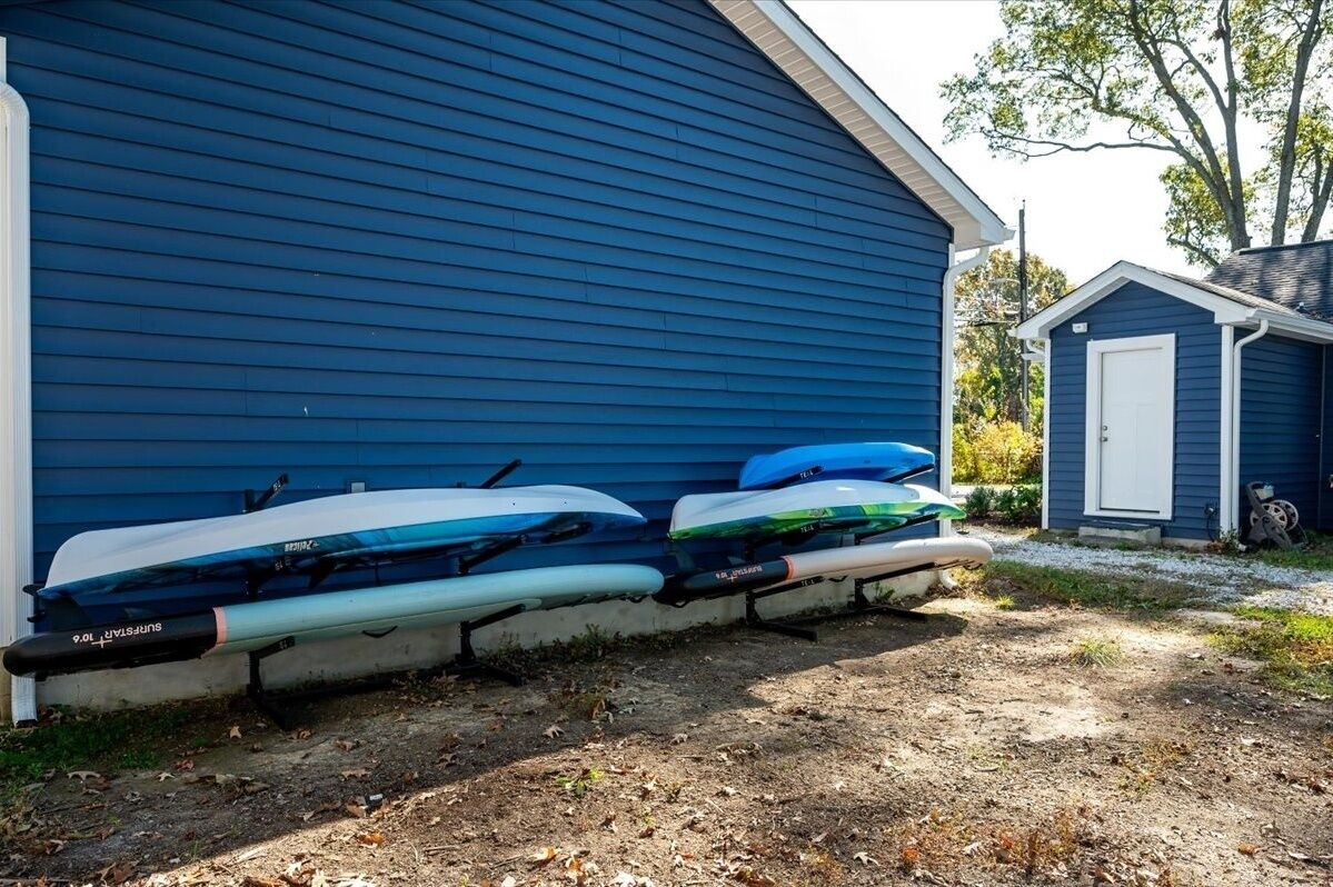 A blue building with two kayaks and a small shed in the background.