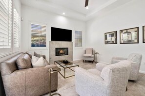 A modern living room with a fireplace, a sofa, armchairs, and a coffee table. - Desert Oasis: Close to Pools, Golf and Coachella! (La Quinta)