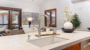 A modern kitchen with a large sink, wooden cabinets, and a dining area with a sofa and a vase of flowers. - Luxury Year Round Deer Valley, Jordanelle Retreat Sleeps 10, Hot Tub, Games Room (Heber City)