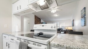 Una cocina moderna con armarios blancos, estufa integrada y encimera de granito.