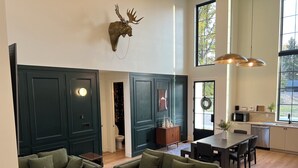 A modern living room with green sofas, a wooden coffee table, and a mounted deer head. - The Nordic Nest on the Greenbelt (Boise)
