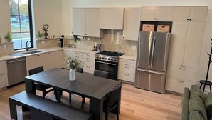 A modern kitchen with a central island, stainless steel appliances, and pendant lighting. - The Nordic Nest on the Greenbelt (Boise)
