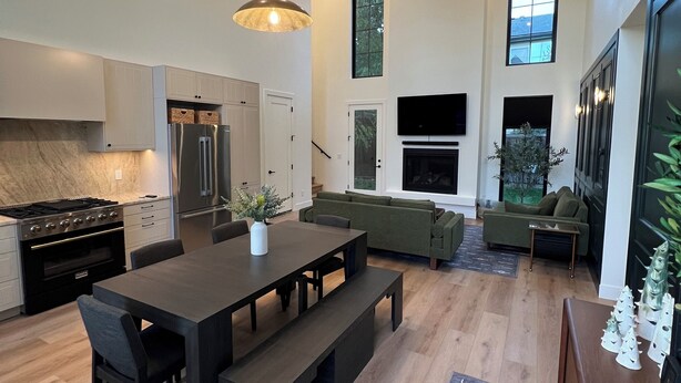 A modern kitchen with a dining area, a large window, and a mounted deer head. - The Nordic Nest on the Greenbelt (Boise)