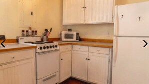 Una cocina con armarios blancos, microondas, estufa y refrigerador.