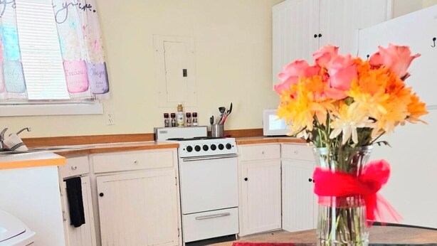 Una cocina con armarios blancos, una estufa y un comedor con una mesa redonda y sillas.