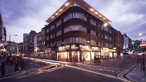 Un hôtel à plusieurs étages, doté d’une façade incurvée, de boutiques au rez-de-chaussée et d’un panneau indiquant qu’il est interdit d’y entrer.