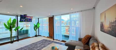 A modern living room with a large window, a flat-screen TV, a sofa, and a coffee table.