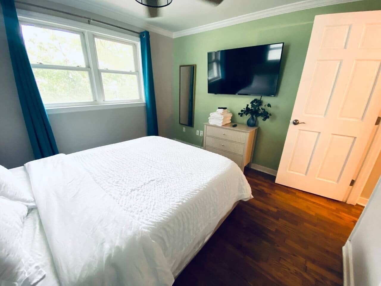 Un dormitorio con cama, cómoda, televisor y puerta.