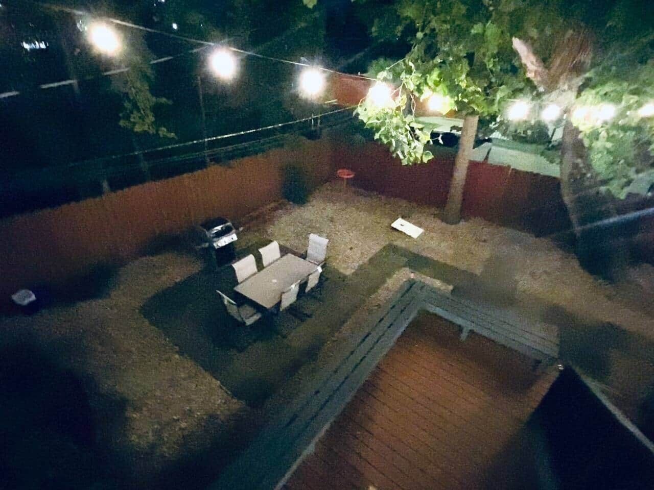 An outdoor patio area with a table and chairs, surrounded by a brick wall and a tree.
