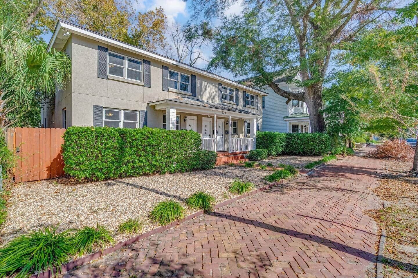 A two-story house with a covered porch, a gravel driveway, and a brick pathway.