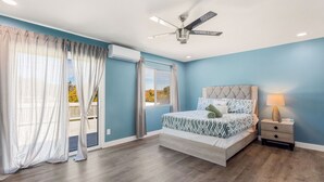 A bedroom with a bed, a nightstand, a ceiling fan, and a view of the outdoors. - Lakeview Retreat in Elsinore with Pool & Hot Tub (Lake Elsinore)