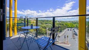 Een balkon met een tafel en stoelen, een weg in het zicht en een heldere lucht.