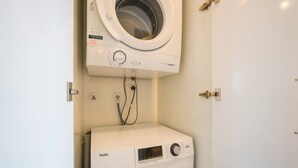 Een kleine wasruimte met een voorlader wasmachine en een droger met bovenlader.