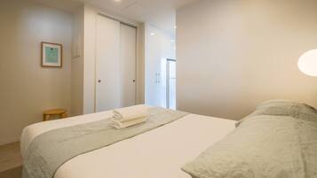 Et hotelværelse med en seng, en lille skammel, et indrammet certifikat på væggen og en dør, der fører til en balkon.