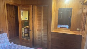 Een houten kamer met een bed, een kaptafel en een spiegel.