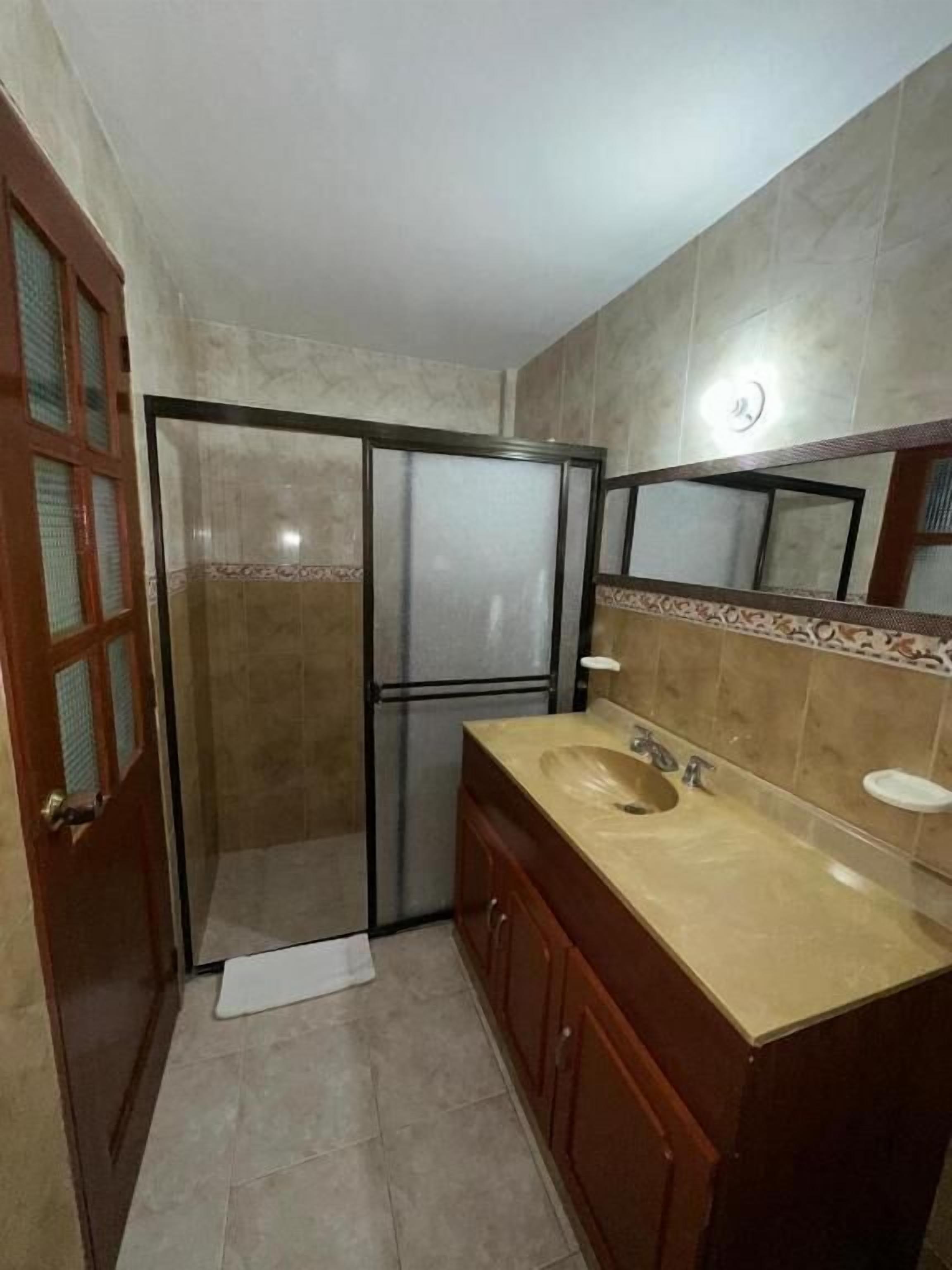 Ein Badezimmer mit Dusche, Waschbecken und Spiegel.