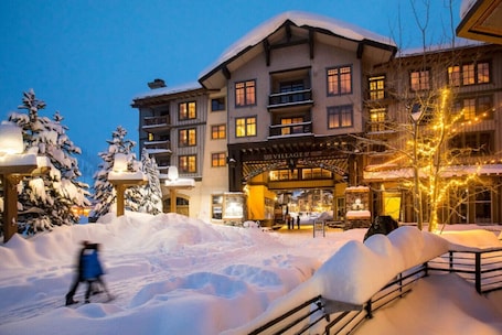 A multi-story hotel with a snow-covered entrance and illuminated exterior.. Palisades Village Condo | Walk to Tram & Trails