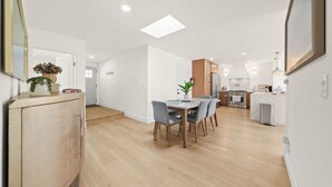 A modern kitchen with a central island, wooden cabinets, and a dining area with a table and chairs. - IMPERIAL HOUSE (San Diego)
