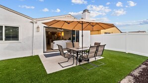 A patio with a table and chairs, a covered umbrella, and a view into the house. - IMPERIAL HOUSE (San Diego)