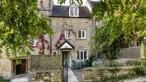 A stone house with ivy-covered walls, a wooden door, and a small garden with a table and chairs. - Archway House - Blockley, Moreton-in-Marsh (Blockley)