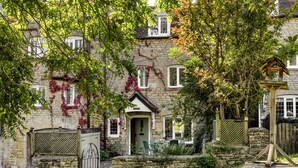 A stone building with ivy-covered walls, a wooden gate, and a small garden area with a bench and table. - Archway House - Blockley, Moreton-in-Marsh (Blockley)