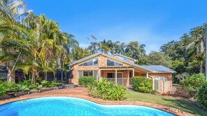 A house with a swimming pool, surrounded by lush greenery and palm trees. - Tropic Lodge by Charlesworth (Coffs Harbour)