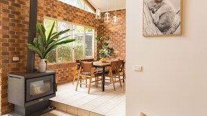 A cozy room with a brick wall, a wooden dining table, chairs, and a large window. - Tropic Lodge by Charlesworth (Coffs Harbour)