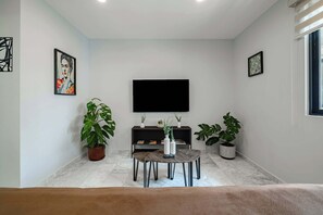 A living room with a flat-screen TV, a coffee table, and potted plants. - Amazing 2BR Apt in Roma Norte - Yoga Room (Mexico City)
