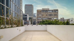 A rooftop terrace with a view of surrounding buildings, including a tall office building and a shorter residential structure. - Brand New 2 BR Condo in Reforma - Queen Beds (Mexico City)