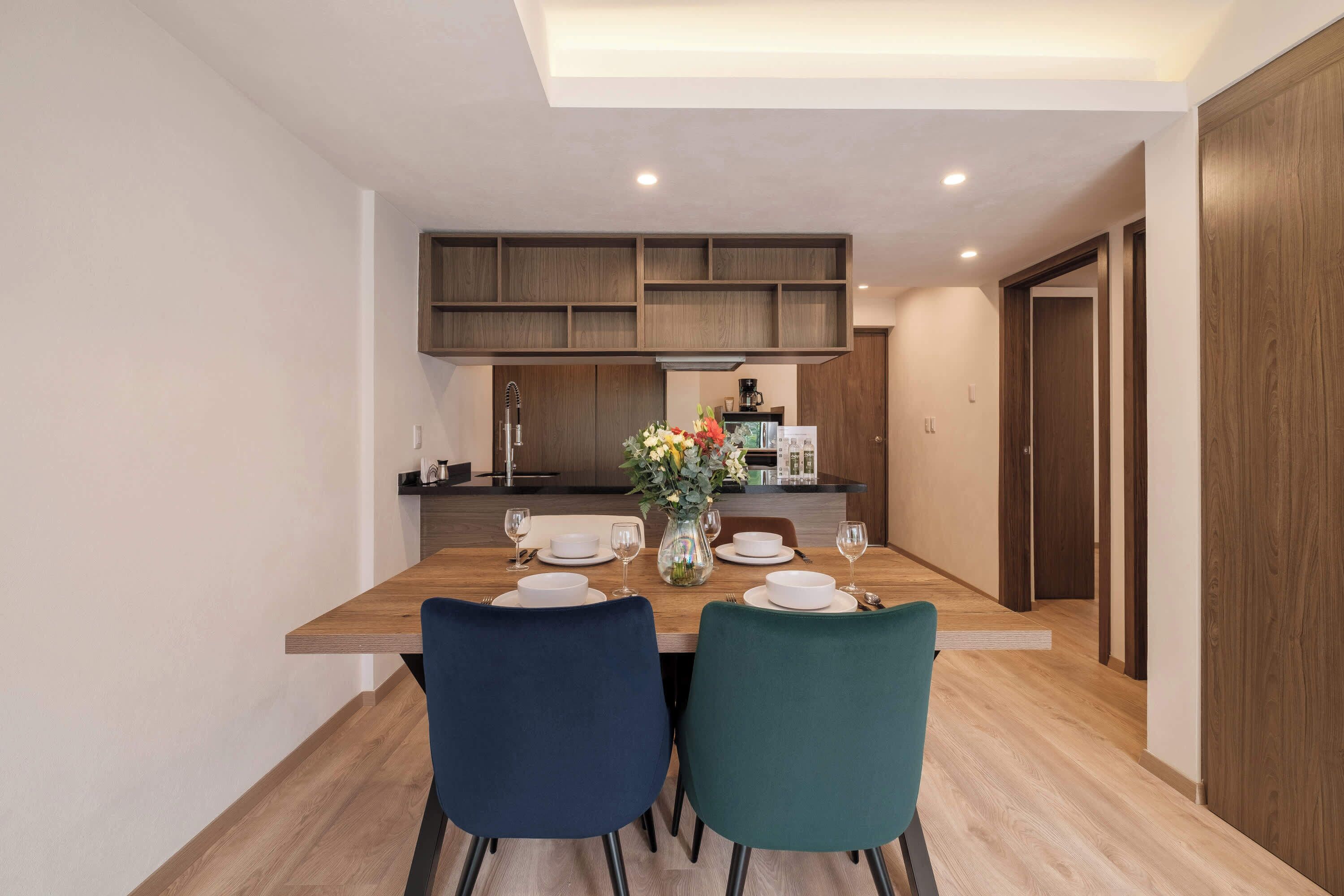 A modern dining area with a wooden table, two chairs, and a vase of flowers.