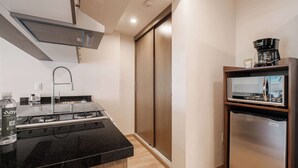 A compact kitchen with a black countertop, stainless steel appliances, and a wooden sliding door closet. - Brand New 2 BR Condo in Reforma - Queen Beds (Mexico City)