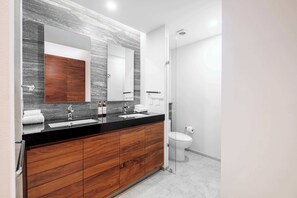 A modern bathroom with a double sink, wooden vanity, large mirror, and a glass shower enclosure. - Redesigned 1BR Condo in Polanco - Pool Gym - Padel (Mexico City)