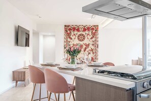A modern kitchen with a central island, stainless steel appliances, and a decorative wall hanging. - Redesigned 1BR Condo in Polanco - Pool Gym - Padel (Mexico City)