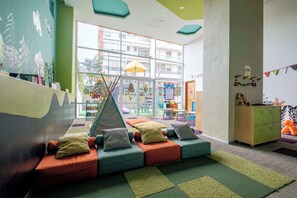 A children's play area with colorful seating, a slide, and a view of the outside. - Redesigned 1BR Condo in Polanco - Pool Gym - Padel (Mexico City)