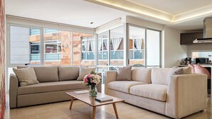 Uma sala de estar moderna com dois sofás, uma mesa de centro e janelas amplas.