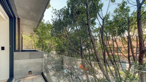 A balcony with a glass railing, a concrete floor, and trees in the background. - Centric 2 BR Condo in the Heart Roma Norte (Mexico City)