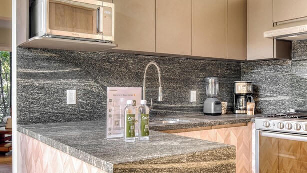 A kitchen with a granite countertop, a built-in microwave, a coffee maker, and a stove. - Centric 2 BR Condo in the Heart Roma Norte (Mexico City)