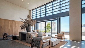 A spacious living area with a large window, a wooden wall, and a modern sofa set. - Luxury Studio - Pool - Revolution Monument View (Mexico City)