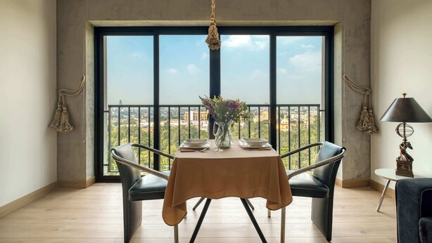 Ein Essbereich mit Tisch für zwei Personen, einer Blumenvase und Blick durch große Fenster.